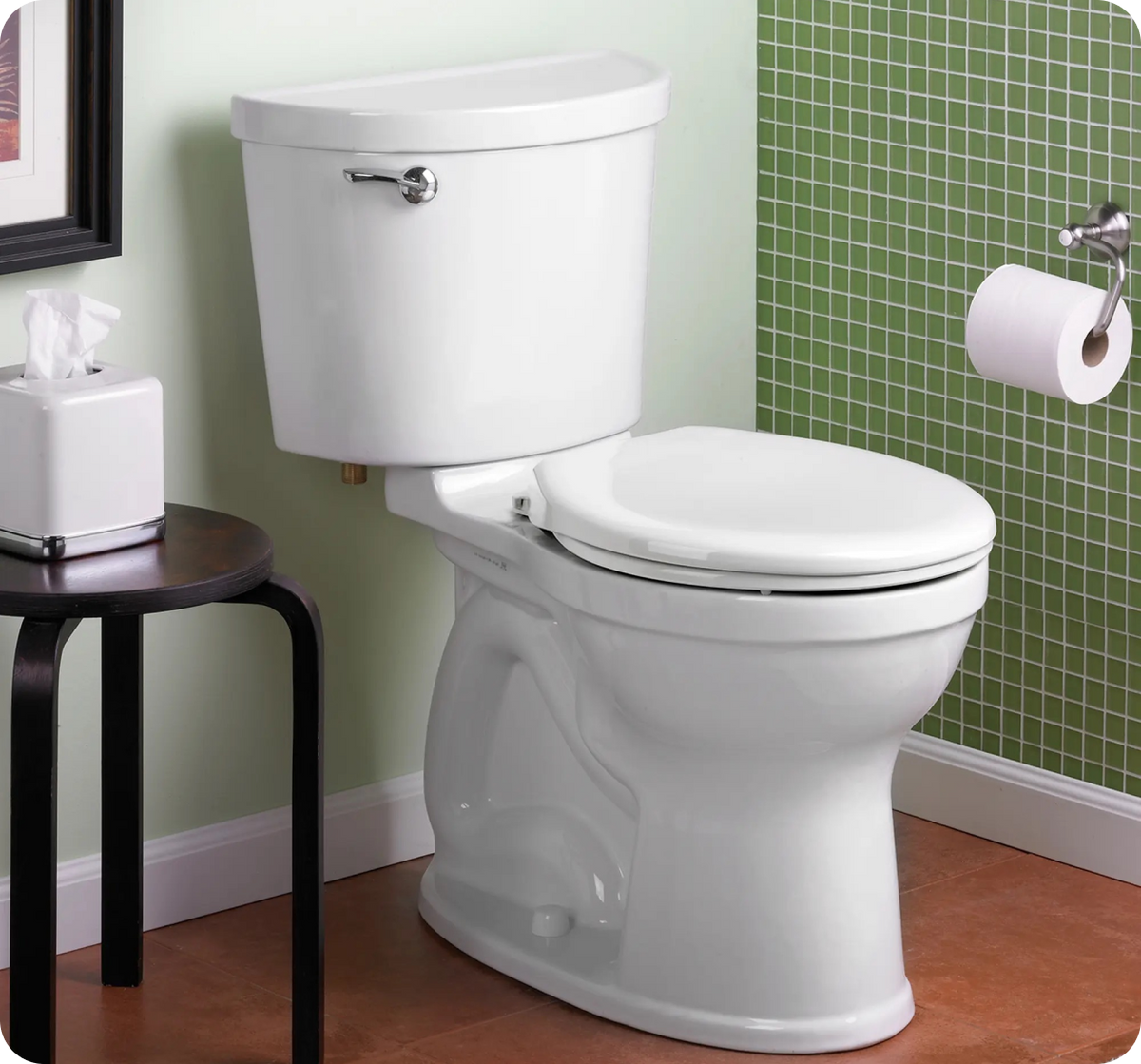 White toilet in a bathroom with green tiled wall and wooden floor.